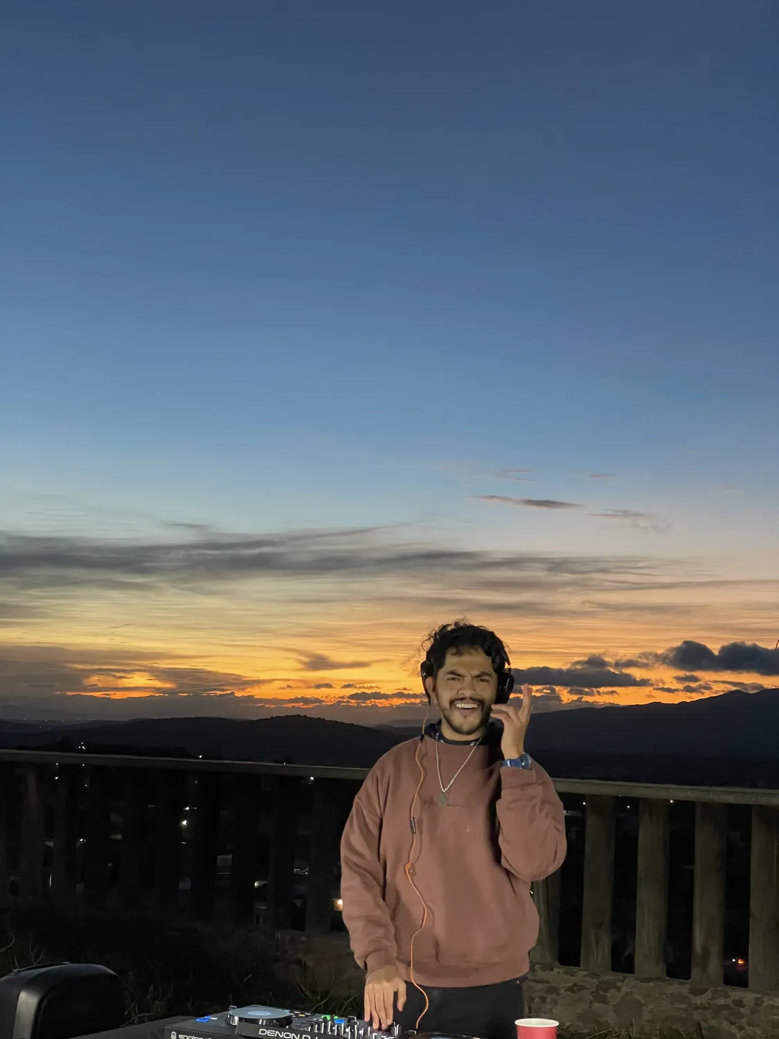 Greek con audífonos al atardecer sobre un mirador